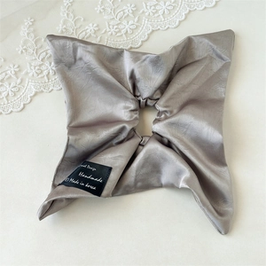Macro detail of elegant champagne satin hair scrunchie with silk texture and woven label