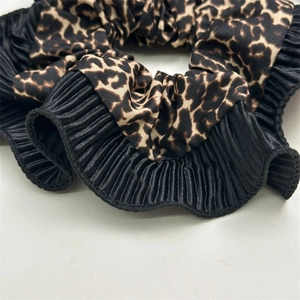 Detailed macro view of leopard print fabric and black pleated satin scrunchie textures