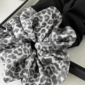 Close-up of leopard print satin scrunchie showing luxury silk texture and gray pattern