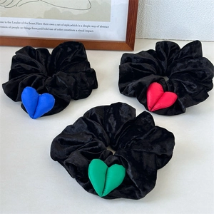 Détails de chouchous en velours noir avec des cœurs en peluche bleus, rouges et verts