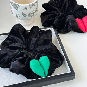 Détail de grands chouchous en velours noir avec des cœurs en peluche rouge et vert