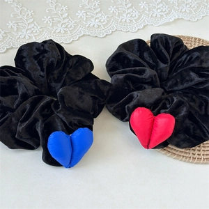 Détail de chouchous en velours noir avec pendentifs en forme de cœur rouge et bleu