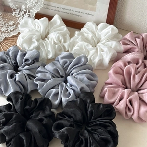 Close-up of assorted silky satin hair scrunchies in white, blue, black, and pink colors