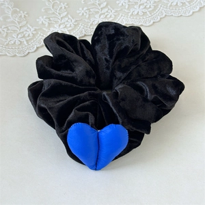 Détail de la texture en velours noir et du pendentif cœur bleu sur le chouchou géant