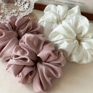 Detail of premium oversized silk satin scrunchies in cream and dusty rose colors