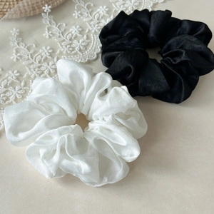 Close-up of black and white satin scrunchies with elegant glossy texture and lace details