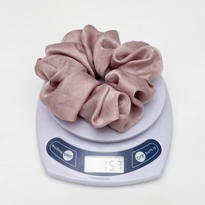 Detailed weight measurement showing 15.7g for the pink satin silk scrunchie accessory
