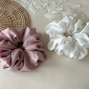 Detailed macro view of large pink and white satin hair scrunchies with elegant glossy texture