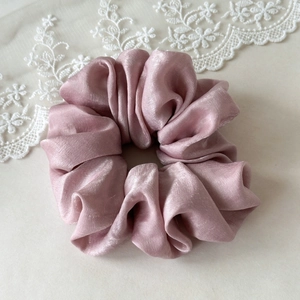 Detailed close-up of premium satin scrunchie in dusty rose with elegant folds