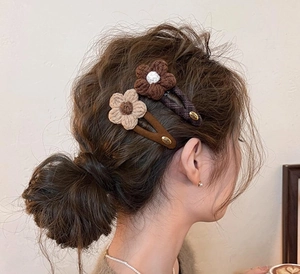 Detail view of handmade knitted flower hair clips with pearls on a model side profile