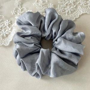 Detailed close-up of thick silver grey satin scrunchie with soft pearl luster and lace