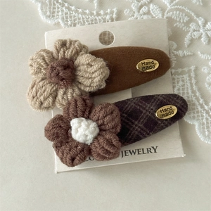 Detail of handmade crochet flower hair clips with gold metal tag on display card