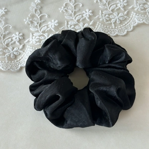 Detailed view of the large black satin hair scrunchie with elegant pleated fabric texture