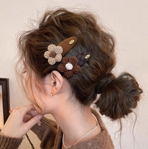 Handmade knitted flower hair clips set in brown and beige on a stylish bun hairstyle