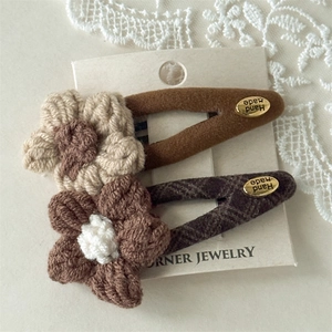 Detailed view of handmade knitted flower hair clips with woolen fabric and metal tags