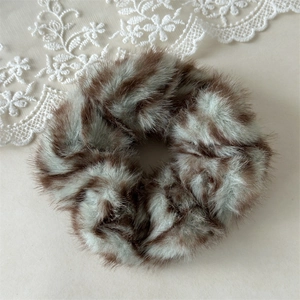 Close-up of zebra pattern plush scrunchie showing soft faux fur texture and fuzzy fabric