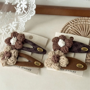 Detailed macro view of handmade crochet flower hair clips in caramel brown and beige colors