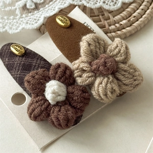 Close-up of handmade crochet flower hair clips with elegant Hand Made golden metal labels