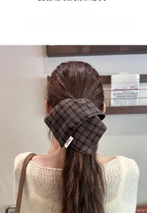 Close-up of a large vintage brown plaid bow scrunchie tied on a low ponytail hair