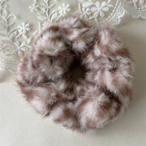 Detailed close-up of plush brown leopard print scrunchie with soft faux fur texture