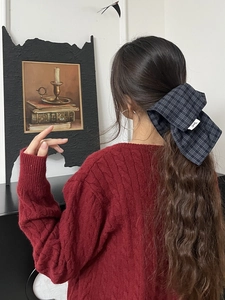Detail shot of a dark checkered oversized bow hair scrunchie on long wavy hair
