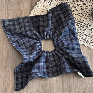 Detailed close-up of blue-green checkered scrunchie fabric with small brand tag