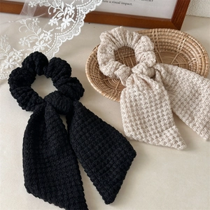 Detail showing hand-knitted crochet bow hair ties with textured weave in black and beige