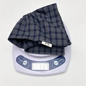 Detail showing a blue and grey plaid fabric hair scrunchie weighing 33.7g on a scale