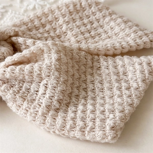 Detail of hand-knitted cream hair tie showing three-dimensional waffle texture