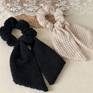 Detail of handmade crochet bow hair scrunchies showing intricate knit texture in black and beige