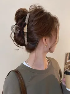 Detail of grey fabric hair claw with brown velvet bow and white label on messy bun