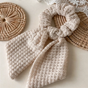 Close-up of handmade crochet bow scrunchie in beige cotton yarn with textured weave