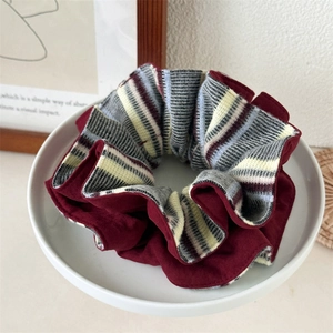Détail d'un chouchou en tricot bordeaux et rayé avec une texture douce sur un plateau