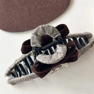 Close-up of velvet bow hair claw clip featuring linen texture and black metal spring