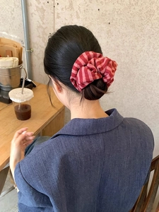Detail of red and pink striped knit scrunchie worn on a high ponytail for women