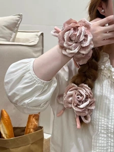 Vue détaillée du chouchou rose en velours avec texture douce sur la main