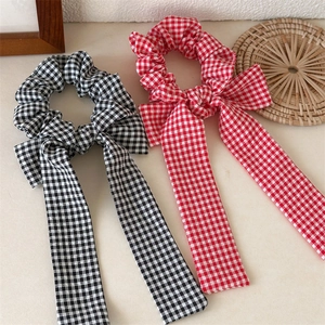 Detail of plaid bow scrunchies in black-white and red-white cotton fabric on a desk