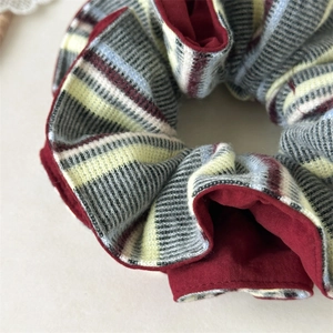 Gros plan d'un chouchou en tricot rayé bordeaux double couche aux plis moelleux