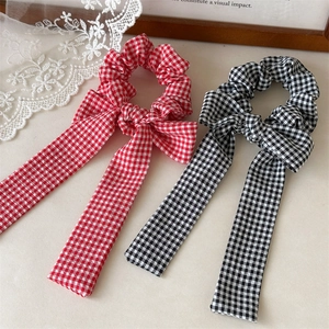 Detail of gingham patterned hair scrunchies with long ribbons in red and black colors
