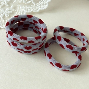 Close-up of five blue elastic hair ties with red heart patterns on white lace background