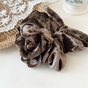 Gros plan sur un chouchou en velours marron en forme de rose avec une texture douce et chic