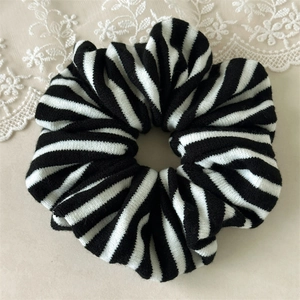 Detail of knitted hair scrunchie with classic black and white stripes on lace background