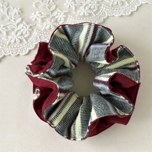 Détail d'un chouchou tricoté vintage avec velours bordeaux et motifs à rayures