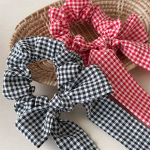Detail of red and black checkered plaid scrunchies with long ribbons on a straw tray