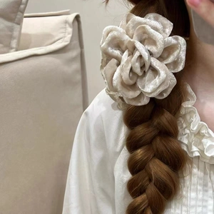 Détail de l'élastique à cheveux en velours champagne porté sur une coiffure tressée