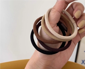 Dettaglio di cinque elastici per capelli senza cuciture in toni terra sfumati e texture