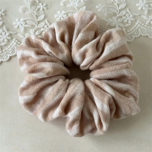 Detail of striped knitted scrunchie showing soft texture and cozy beige fabric