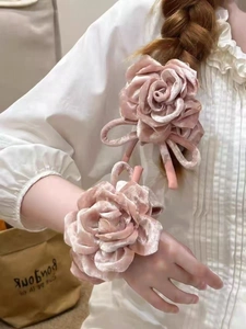 Vue détaillée des chouchous roses en velours avec roses faits main sur chemisier blanc