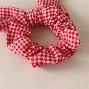 Close-up of red and white checkered fabric hair scrunchie with knot bow detail