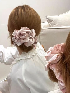 Détail d'un chouchou rose en velours avec rose porté sur une queue de cheval élégante